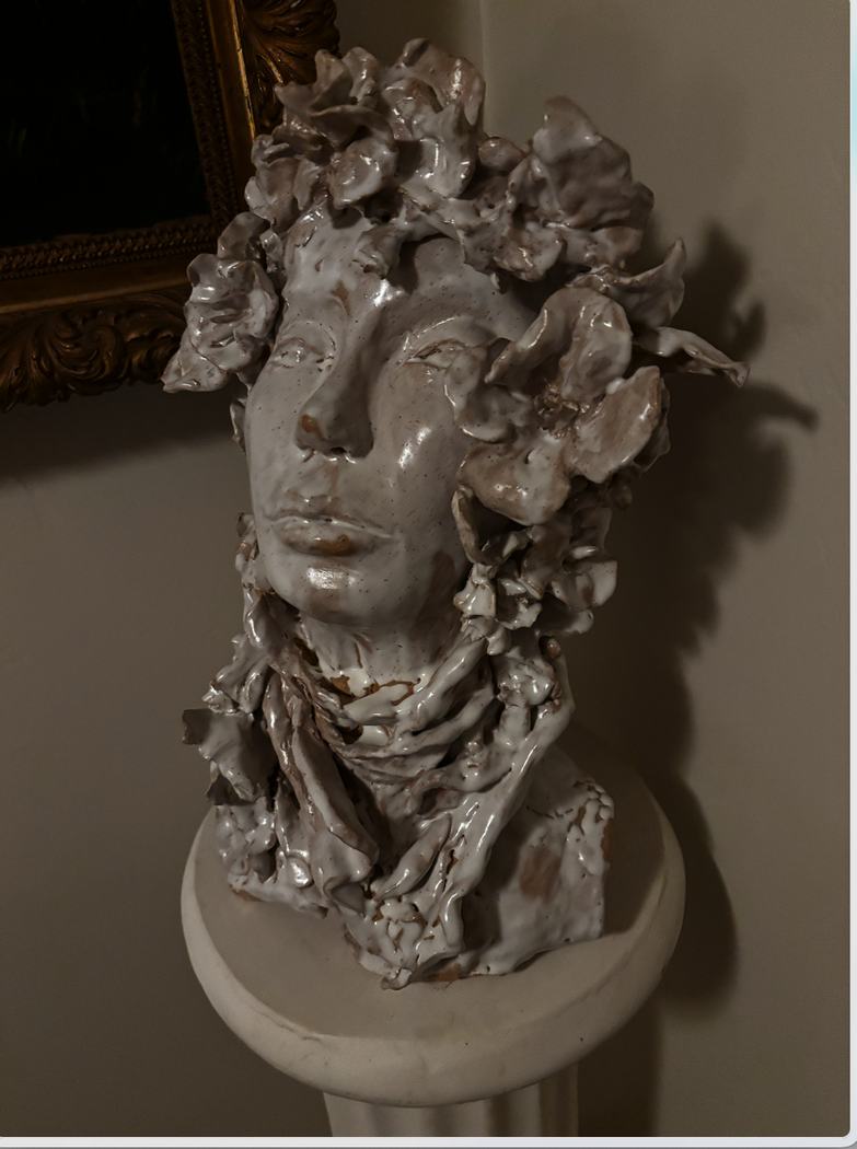 Glazed ceramic bust with large sculpted flowers and a wrapped collar